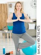 young pregnant woman practicing yoga at home. Стоковое фото, агентство Ingram Publishing / Фотобанк Лори