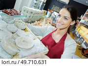 happy brunette seller proposing different types of cheese. Стоковое фото, агентство Ingram Publishing / Фотобанк Лори