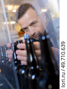 male worker in apron operating bottling equipment on brewery. Стоковое фото, агентство Ingram Publishing / Фотобанк Лори