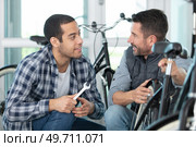 two happy mechanics with tools in a bike repair station. Стоковое фото, агентство Ingram Publishing / Фотобанк Лори