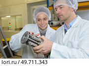 male and female technicians looking at metal component. Стоковое фото, агентство Ingram Publishing / Фотобанк Лори