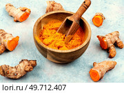 Fresh turmeric root in wooden bowl and turmeric powder. Curcuma longa Linn.. Turmeric root and curcuma powder, medicine herb. Стоковое фото, агентство Ingram Publishing / Фотобанк Лори