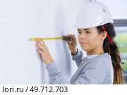woman builder measuring the wall. Стоковое фото, агентство Ingram Publishing / Фотобанк Лори