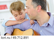 Man playing guitar, child leaning on his shoulder. Стоковое фото, агентство Ingram Publishing / Фотобанк Лори