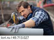 young male plumber sawing through pvc pipe. Стоковое фото, агентство Ingram Publishing / Фотобанк Лори