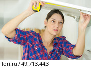 portrait of woman measuring cupboard door. Стоковое фото, агентство Ingram Publishing / Фотобанк Лори