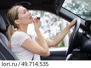 female driver applying lipstick in visor mirror. Стоковое фото, агентство Ingram Publishing / Фотобанк Лори