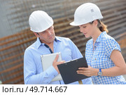 Man and woman in hardhats looking at clipboard. Стоковое фото, агентство Ingram Publishing / Фотобанк Лори