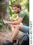 man whittling stick with a blade in the forest. Стоковое фото, агентство Ingram Publishing / Фотобанк Лори