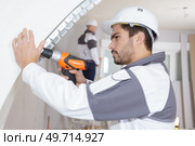 young man drilling wall indoors. Стоковое фото, агентство Ingram Publishing / Фотобанк Лори
