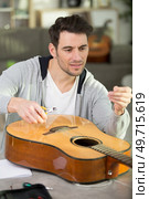 handsome man repairing guitar at workshop. Стоковое фото, агентство Ingram Publishing / Фотобанк Лори