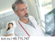 doctor examining x-rays in patients room. Стоковое фото, агентство Ingram Publishing / Фотобанк Лори