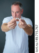 an adult man breaking cigarette. Стоковое фото, агентство Ingram Publishing / Фотобанк Лори
