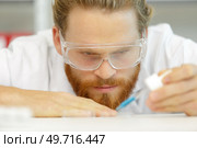 lab worker using pipette to add blue liquid in test-tube. Стоковое фото, агентство Ingram Publishing / Фотобанк Лори