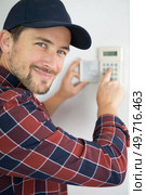smily young male plumber fixing thermostat. Стоковое фото, агентство Ingram Publishing / Фотобанк Лори