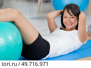 smiling young woman doing abdominal crunch. Стоковое фото, агентство Ingram Publishing / Фотобанк Лори