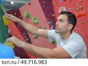 free climber young man climbing artificial boulder in gym. Стоковое фото, агентство Ingram Publishing / Фотобанк Лори