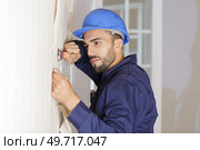 male contractor removing wallpaper in residential room. Стоковое фото, агентство Ingram Publishing / Фотобанк Лори