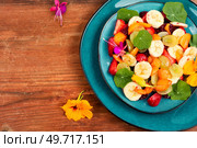 Vitamin fruit salad with banana, strawberries, grapes and nasturtium. Space for text.. Fruit salad with nasturtium, copy space. Стоковое фото, агентство Ingram Publishing / Фотобанк Лори