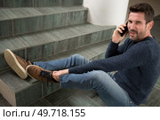man fallen down staircase calling for help on his smartphone. Стоковое фото, агентство Ingram Publishing / Фотобанк Лори