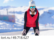 Calm athletic female in warm clothes and sunglasses leaning on knees recovering breathe while jogging in nature. Modern sportive woman in winter nature. Стоковое фото, агентство Ingram Publishing / Фотобанк Лори