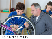 man working in bike workshop fixing bicycle spokes. Стоковое фото, агентство Ingram Publishing / Фотобанк Лори