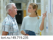 young lady questioning senior man regarding notice on board. Стоковое фото, агентство Ingram Publishing / Фотобанк Лори