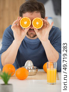 cheerful young man covering his eyes with oranges. Стоковое фото, агентство Ingram Publishing / Фотобанк Лори