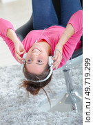 woman listening to headphones whilst on a chair. Стоковое фото, агентство Ingram Publishing / Фотобанк Лори