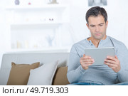 happy man browsing in a tablet sitting on a couch. Стоковое фото, агентство Ingram Publishing / Фотобанк Лори