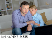 Son falling asleep on father watching television. Стоковое фото, агентство Ingram Publishing / Фотобанк Лори
