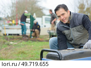Builder kneeling by a generator. Стоковое фото, агентство Ingram Publishing / Фотобанк Лори
