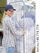 happy young female employee carrying laundry basket in laundromat. Стоковое фото, агентство Ingram Publishing / Фотобанк Лори