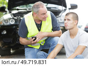 man angry with nonchalant young man by broken down car. Стоковое фото, агентство Ingram Publishing / Фотобанк Лори