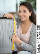 positive woman is measuring her suitcase. Стоковое фото, агентство Ingram Publishing / Фотобанк Лори
