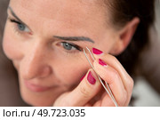 woman plucking her eyebrows with tweezer. Стоковое фото, агентство Ingram Publishing / Фотобанк Лори