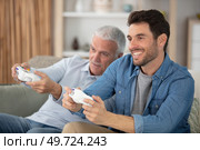 excited millennial man and senior father playing videogames. Стоковое фото, агентство Ingram Publishing / Фотобанк Лори