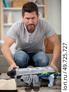 man tries to close a full suitcase. Стоковое фото, агентство Ingram Publishing / Фотобанк Лори