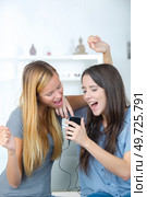 amazed roommates watching offers on line with a smart phone. Стоковое фото, агентство Ingram Publishing / Фотобанк Лори