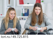 sisters playing video games in living room. Стоковое фото, агентство Ingram Publishing / Фотобанк Лори