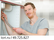 happy young male plumber fixing faucet in kitchen. Стоковое фото, агентство Ingram Publishing / Фотобанк Лори