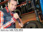 car mechanic screwing or unscrewing car wheel. Стоковое фото, агентство Ingram Publishing / Фотобанк Лори