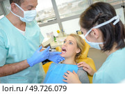 dentist curing a woman patient in the dental office. Стоковое фото, агентство Ingram Publishing / Фотобанк Лори