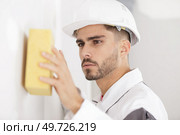 young male builder sponging wall surface. Стоковое фото, агентство Ingram Publishing / Фотобанк Лори