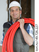 happy electrician with red wires on a construction site. Стоковое фото, агентство Ingram Publishing / Фотобанк Лори