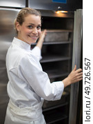 a female chef opens the fridge. Стоковое фото, агентство Ingram Publishing / Фотобанк Лори