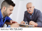 senior and young man fixing the door with screwdriver. Стоковое фото, агентство Ingram Publishing / Фотобанк Лори