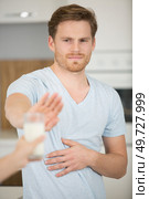 young man with milk allergy refusing glass. Стоковое фото, агентство Ingram Publishing / Фотобанк Лори