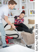 young man vacuuming while woman is resting on a couch. Стоковое фото, агентство Ingram Publishing / Фотобанк Лори