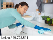 concentrated woman scrubbing the bar in kitchen. Стоковое фото, агентство Ingram Publishing / Фотобанк Лори